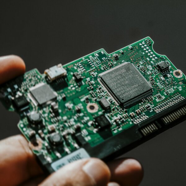 Close-up view of a green circuit board held by a hand, showcasing technology details.